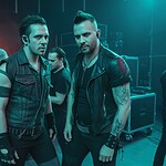 Zwei männliche Rockmusiker bereiten sich hinter der Bühne auf einen Auftritt vor, umgeben von Technikern und Bühnenausrüstung.